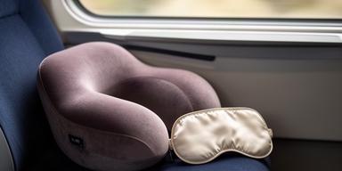 Nackenkissen und Schlafmaske auf einem Sitzplatz im Zug